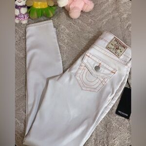 White True Religion jeans with a peach-colored or pink stitching.
